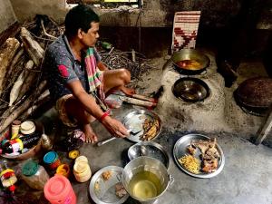 KākdwīpSatrangi Homestay Sundarban的男人在餐桌上用碗饭做饭
