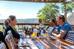 阿马卡拉保护区Woodbury Lodge – Amakhala Game Reserve的一群坐在餐桌上吃食物的人
