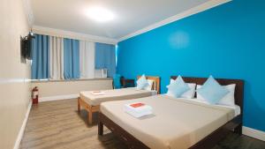 马尼拉RedDoorz @ Manila Airport Hotel的一间设有两张床和蓝色墙壁的客房