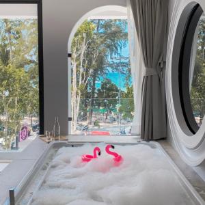 芭东海滩Anona Beachfront Phuket Resort-SHA EXTRA PLUS的带窗户的客房内配有粉红色火烈鸟浴缸