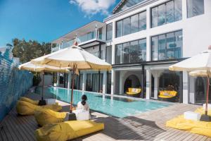 芭东海滩Anona Beachfront Phuket Resort-SHA EXTRA PLUS的一座带黄色椅子和遮阳伞的游泳池的建筑