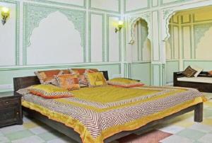 斋浦尔拉尼泰姬陵酒店的一间卧室配有一张带色彩缤纷枕头的大床