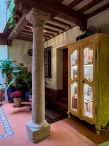 托莱多阿尔穆尼亚德善秘古尔酒店的一间设有柱子的房间和一个带书籍的橱柜