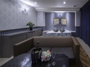 福山HOTEL xcell的一间卧室配有一张床、一张沙发和一张桌子