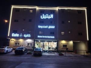 利雅德Al Bateel Furnished Apartments的停车场内停放汽车的大型建筑