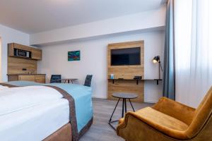 埃森Trip Inn Hotel & Suites Essen的配有一张床和一把椅子的酒店客房