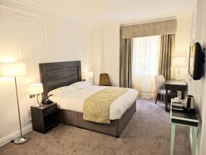 伦敦阿斯特法院酒店的酒店客房设有一张大床和一张书桌。