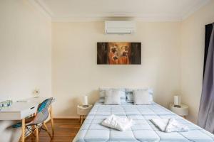 卧龙岗Wollongong station holiday house with Wi-Fi,75 Inch TV, Netflix,Parking,Beach的白色的客房配有床、书桌和桌子