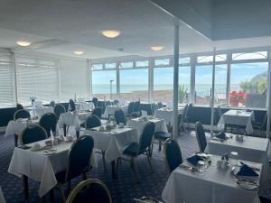 尚克林海峡美景酒店的餐厅设有白色的桌椅和窗户。