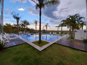 弗洛里亚诺波利斯Cobertura Frente Mar Campeche - 3 quartos, jacuzzi的庭院中棕榈树的游泳池