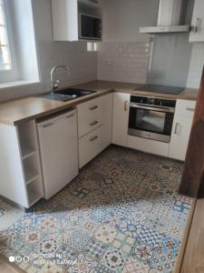瓦兹河畔欧韦Appartement cosy au coeur d'Auvers-Sur-Oise的厨房配有白色橱柜和瓷砖地板。