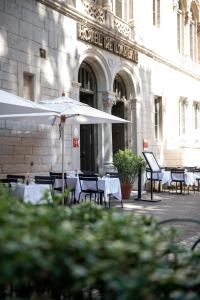 里昂Hôtel de l'Abbaye Lyon - Boutique Hôtel的大楼前的餐厅,配有桌子和遮阳伞