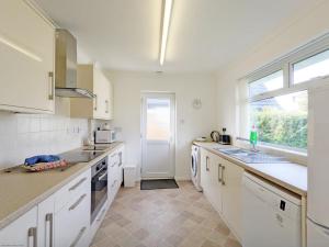 博格诺里吉斯11 Shorecroft, Aldwick的厨房配有白色橱柜、水槽和窗户。