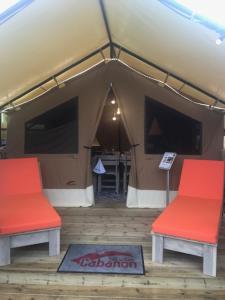 勒格罗-迪鲁瓦Oh! Campings - L'Espiguette的配有2把红色椅子和1张桌子的帐篷