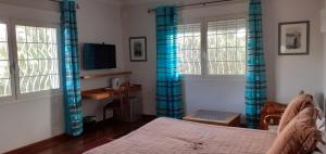安齐拉贝Chambre d'Hôte Villa Maritampona的一间卧室配有蓝色窗帘、一张床和一张书桌