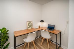 布恩The Wanderer Guesthouse的一张带笔记本电脑和两把白色椅子的桌子