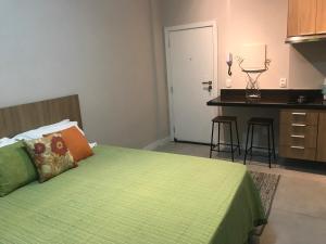 里约热内卢Fantástico STUDIO DIVISA COPACABANA IPANEMA REFORMADO E DECORADO的一间带绿色床的卧室和一间厨房