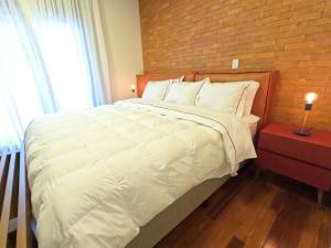 格拉玛多Austin Suites Gramado的卧室配有一张白色大床和砖墙