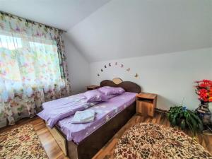鲁克尔Casa de langa rau RUCAR的一间卧室配有一张带紫色床单和地毯的床。