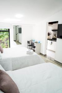 库库塔Hotel Casa Luna的一间白色卧室,配有两张床和厨房