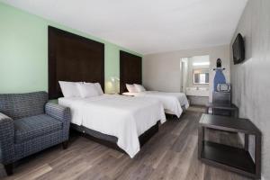 布莱斯维尔Americas Best Value Inn and Suites Blytheville的酒店客房,配有两张床和椅子