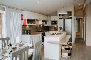 伍德哈尔温泉水疗Casa Di Lusso Luxury lodge的厨房以及带白色橱柜和桌子的用餐室。