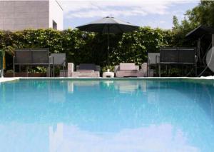 索托德拉马里纳Villa Playa San Juan的一个带遮阳伞和椅子的大型蓝色游泳池