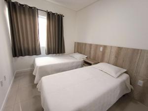 邦比尼亚斯Residencial Natália的酒店客房设有两张床和窗户。