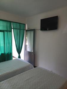 丰沙尔Alojamento Central - Funchal的一间卧室设有两张床,墙上配有电视。