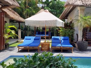 塞米亚克Beautiful Villa Indah的一组蓝色椅子和一把伞,位于游泳池旁