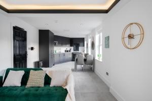 纽伯里Aryas Apartments Newbury的一间带绿色沙发的客厅和一间厨房