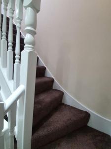 达格纳姆5 Bedroom House by monishortlets的一条有白色栏杆和棕色楼梯的楼梯