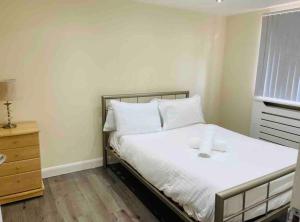 达格纳姆5 Bedroom House by monishortlets的一间卧室配有一张带白色床单的床和一扇窗户。
