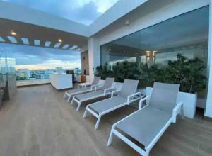 圣多明各1BR Luxury apartment Pool, gym, rooftop Santo Domingo的阳台配有白色椅子,享有城市美景。