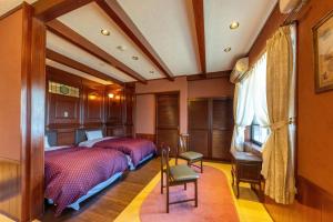 敦贺市Tsuruga Sazanami Resort Chobei的一间卧室配有两张床和一张桌子及椅子