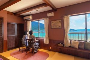 敦贺市Tsuruga Sazanami Resort Chobei的两个人坐在一张桌子上,从窗户望出去