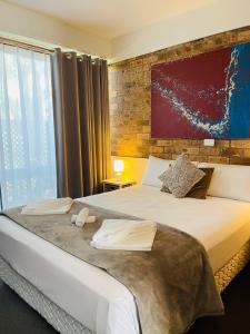 尼尔森湾斯蒂芬斯港汽车旅馆的一间卧室设有一张带砖墙的大床