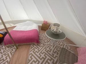 查尔顿Charlton End Bell Tent的帐篷内带一张床和一张桌子的房间