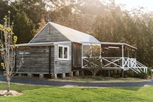 诺拉Picturesque Barn located on the Shoalhaven River的一座带门廊和树的小木房子