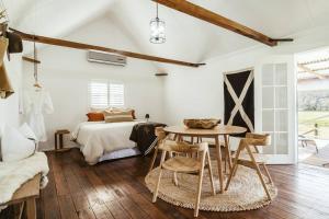 诺拉Picturesque Barn located on the Shoalhaven River的卧室配有一张床和一张桌子及椅子