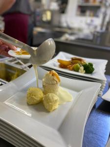 奥西亚歇尔湖畔施泰因多夫霍夫曼希酒店的带有勺子的白色盘子,上面有食物