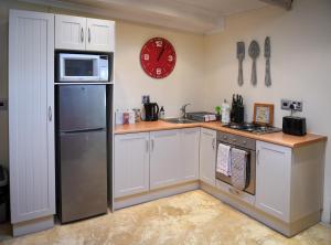 弗朗斯胡克Cabriere Cottage的厨房配有冰箱和墙上的时钟