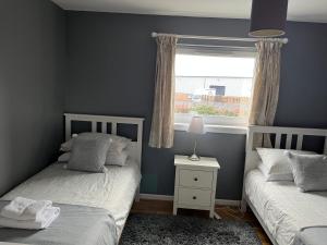 东基尔布赖德Flat Three, 212 Eaglesham Road, East Kilbride, Glasgow的一间卧室设有两张单人床和一个窗户。