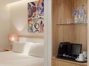 马拉加H10 Croma Málaga的一间酒店客房,配有一张床和架子上的电视