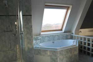 海牙海牙弗莱彻酒店的带浴缸的浴室和窗户。