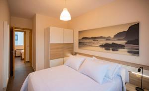 JoveArea Suites的卧室配有一张白色床,墙上挂有绘画作品