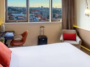 波尔图Mercure Porto Centro Santa Catarina的酒店客房带一张床、椅子和窗户