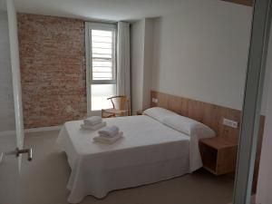 萨洛Vora Salou的白色卧室,配有带毛巾的床