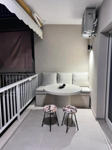 拉格尼西Lagonisi Luxury Apartment by the sea的带阳台的带桌子和2把凳子的房间