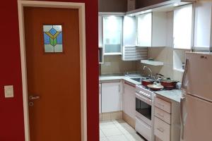 罗萨里奥Departamento luminoso amplio y silencioso.的厨房配有白色橱柜和橙色门